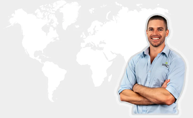 A man in a blue shirt stands in front of a world map